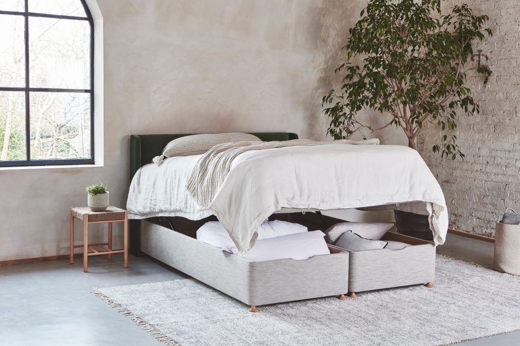 Modern ottoman storage bed in a minimalist bedroom, with the mattress lifted to reveal spacious under-bed compartments for bedding and pillows, ideal for maximising space in small homes.