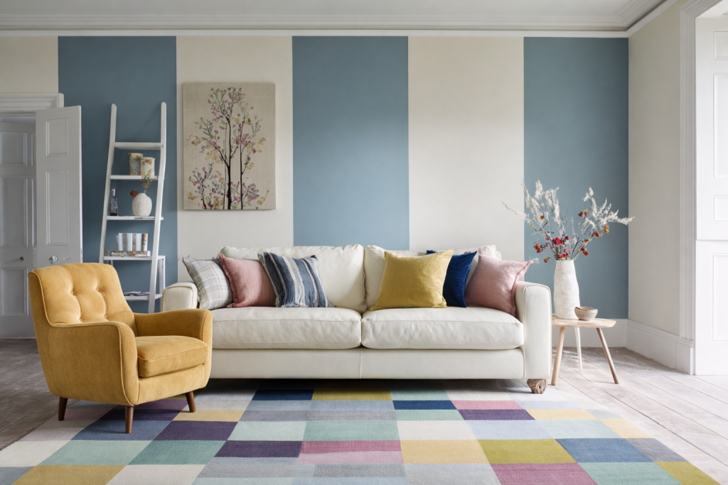 Bright living room with wide blue and cream stripe walls, a multicoloured geometric rug, cream sofa and yellow velvet armchair