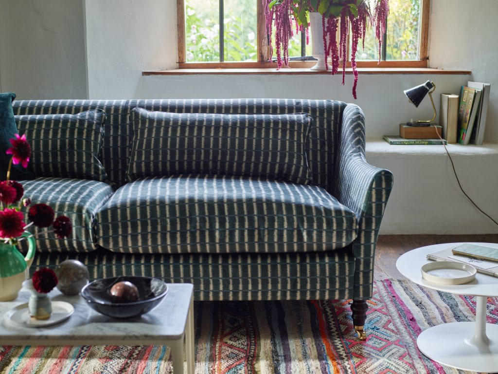 Blue striped sofa on a traditional red and blue striped rug in a cottage interior