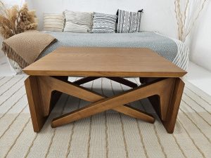 Convertible wooden coffee table with geometric base design, shown in a modern living space, that transforms into a full dining table for a versatile, space-saving solution in small homes.